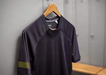 Donker sportshirt van ademend materiaal aan een kleedkamerhaak